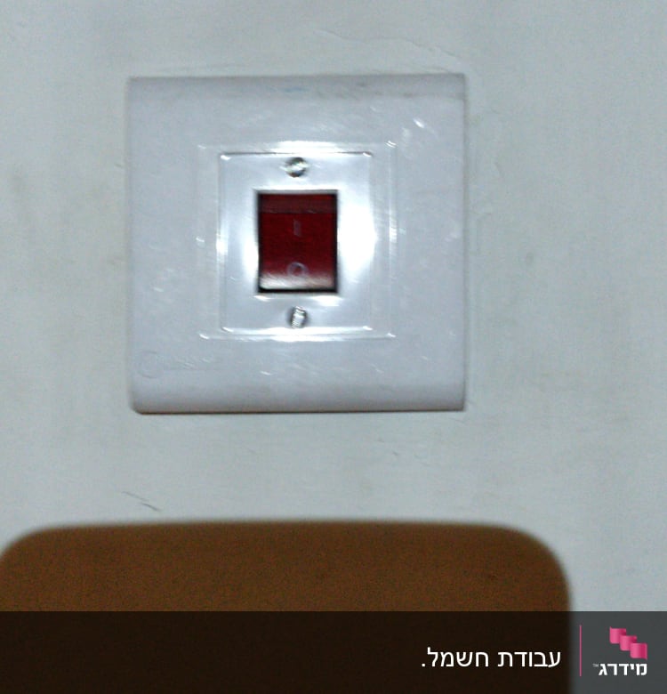 מתג חשמלי עם כיסוי לבן על קיר